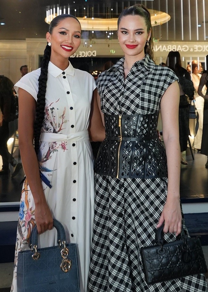 H'Hen Niê (trái) và Catriona Gray quen biết nhau khi cùng là thí sinh dự thi Miss Universe 2018. Năm đó H'Hen Niê dừng chân ở top 5 còn Catriona Gray đăng quang hoa hậu.  Sang đảo quốc sư tử dự sự kiện thời trang quy tụ nhiều nghệ sĩ, người có sức ảnh hưởng trong làng mốt châu Á H'Hen Niê mặc bộ váy trắng hàng hiệu kín đáo, thanh lịch trong khi mỹ nhân người Philippines kết hợp corset da đục lỗ và váy hoạ tiết kẻ carô.