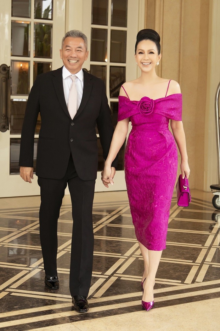 Diễn viên Diễm My diện đầm hồng trễ vai bằng vải gấm. Trang phục được kết hợp với giày hồng ánh kim của Saint Laurent, túi da của Stalvey, hoa tai, nhẫn ngọc trai. Doanh nhân Hà Tôn Đức diện vest đen lịch lãm.