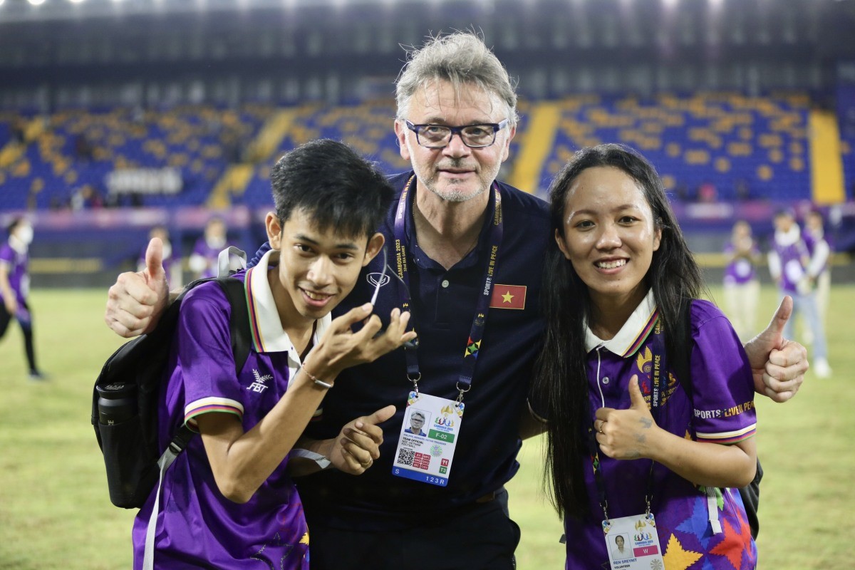 HLV Troussier chụp ảnh cùng các tình nguyện viên Campuchia sau trận đấu.