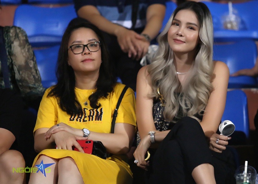 Kỳ Hân (bên phải) nổi bật trên khái đài sân Hàng Đẫy cổ vũ Mạc Hồng Quân trong trận đấu giữa Hà Nội FC và CLB Bình Định ở vòng một giai đoạn hai V-League 2023. Cựu người mẫu quê Sóc Trăng diện bộ đồ đen, tóc xoăn nhuộm màu khói và trang điểm kỹ càng trước khi đến sân.