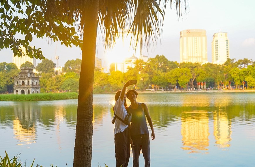 Du khách nước ngoài lưu lại khoảnh khắc mùa Thu bên hồ Hoàn Kiếm. (Nguồn: TTXVN)