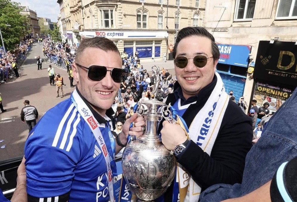 Chủ tịch Leicester City Aiyawatt Srivaddhanaprabha nâng cup cùng tiền đạo đội trưởng Jamie Vardy khi diễu hành trên xe bus. Aiyawatt là con trai cố tỷ phú Vichai Srivaddhanaprabha - người qua đời vì tai nạn máy bay hồi năm 2018.