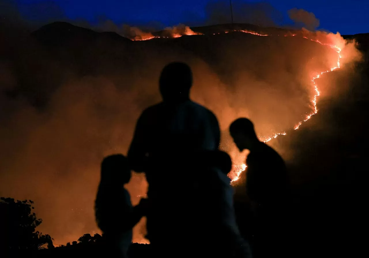 Người dân theo dõi một đám cháy rừng đang lan rộng trên diện tích lớn tại Công viên Quốc gia Núi Bàn, khu vực Tokai, ở Cape Town, Nam Phi, vào ngày 27 tháng 4. (Nguồn: Reuters)