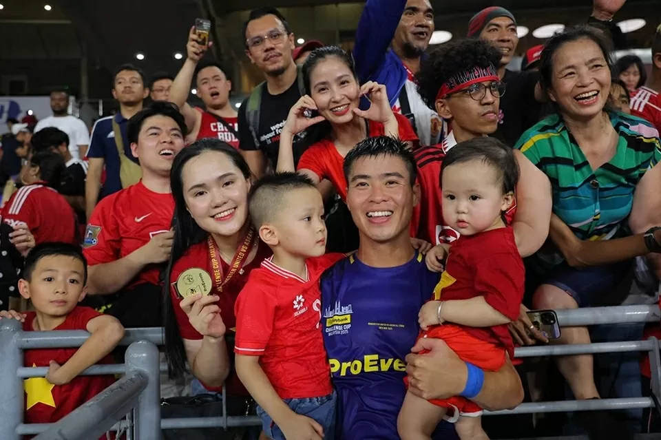 Duy Mạnh tìm đến khu vực khán đài nơi vợ con, bố mẹ và chị gái ngồi để chia vui. Trung vệ CLB Hà Nội đeo huy chương cho bà xã Quỳnh Anh, bế 2 con chụp ảnh kỷ niệm cùng mẹ (góc phải), chị gái (tạo dáng tay hình trái tim) và cháu trai (góc trái).