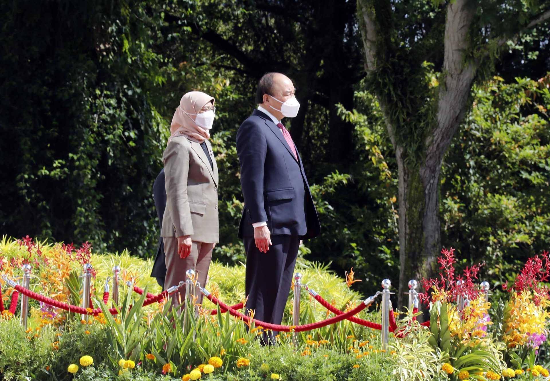 Chủ tịch nước Nguyễn Xuân Phúc và Tổng thống Cộng hòa Singapore Halimah Yacob nghe quân nhạc cử Quốc thiều 2 nước. (Nguồn: TTXVN)