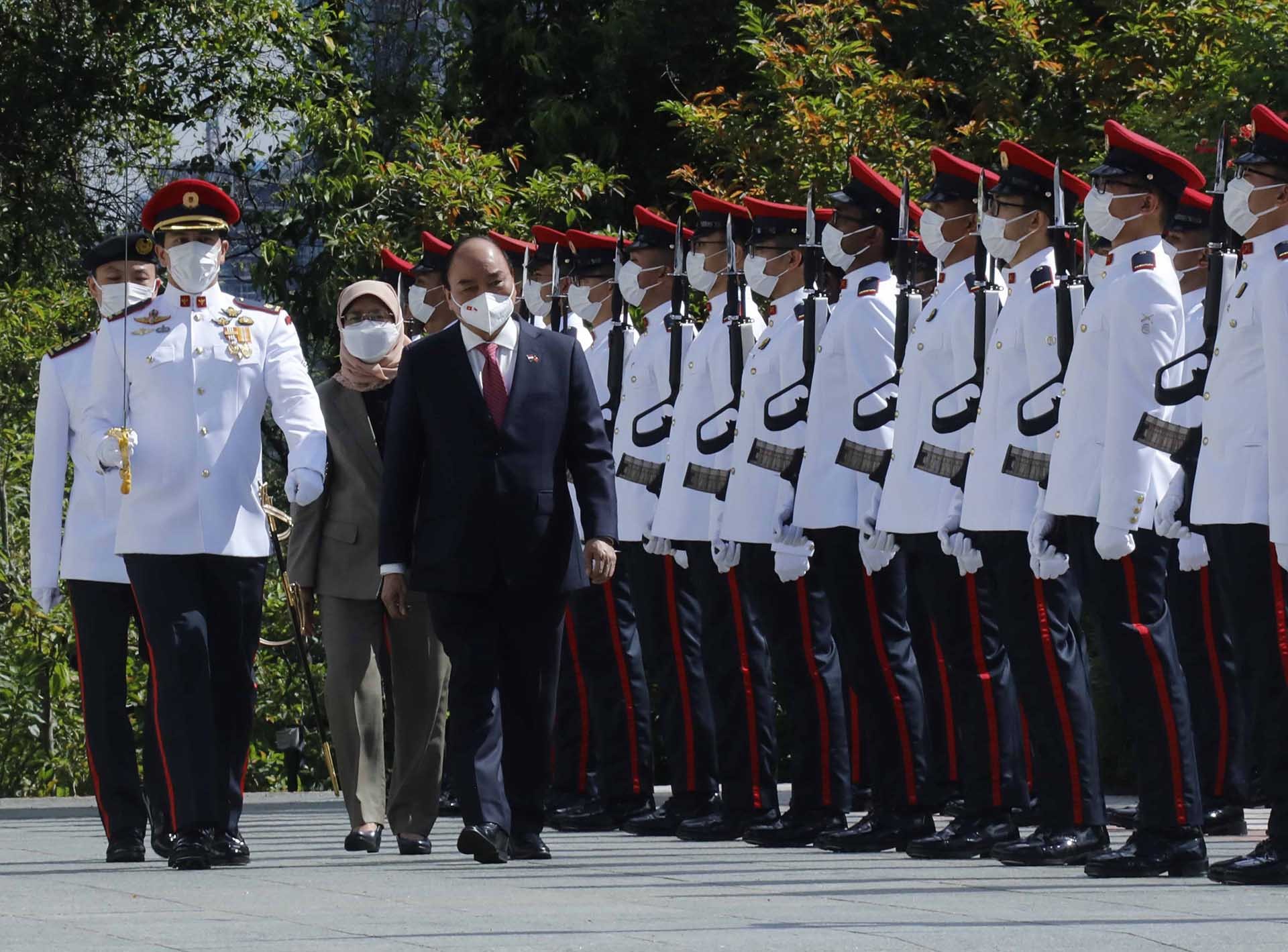 Chủ tịch nước Nguyễn Xuân Phúc và Tổng thống Cộng hòa Singapore Halimah Yacob duyệt đội danh dự. (Nguồn: TTXVN)