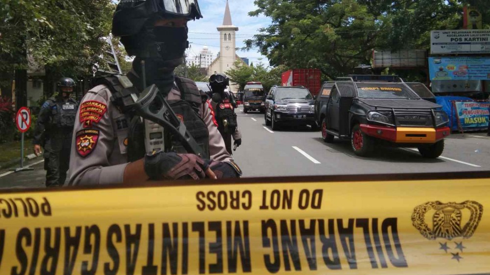 Armed police officers stand guard along a closed road following an explosion outside a Catholic church in Makassar, South Sulawesi province, Indonesia, on March 28.   © Reuters