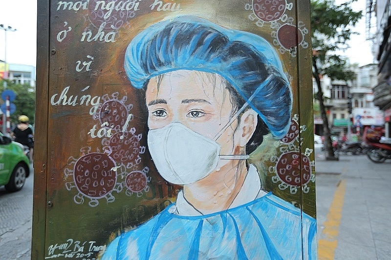 Thông điệp ''Mọi người hãy ở nhà vì chúng tôi'' được để lên bốt điện kèm hình ảnh một nữ bác sĩ đang mang trên mình bộ đồ bảo hộ bít kín trong ngày hè...