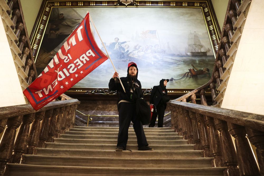 (1.9) Một người biểu tình cầm cờ ủng hộ Tổng thống Donald Trump sau khi xâm nhập vào Điện Capitol ngày 6/1. (Nguồn: Getty Images)