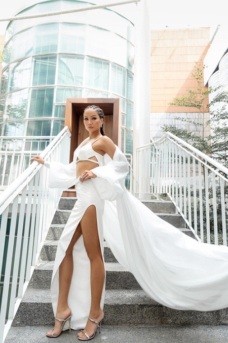 H'Hen Niê phối áo choàng tiệp màu khi diện trang phục kết hợp giữa áo bra biến thể đi cùng chân váy xẻ cao.