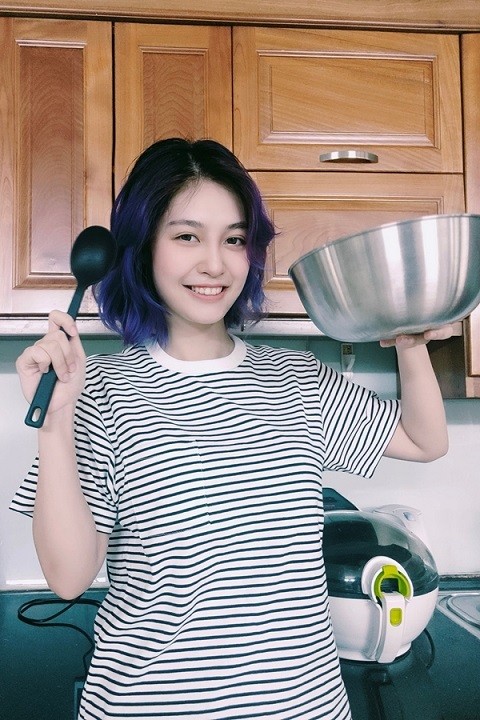 Hằng để mặt mộc, mặc giản dị trong gian bếp. Cô thích thử nghiệm nhiều kiểu tóc và màu tóc.