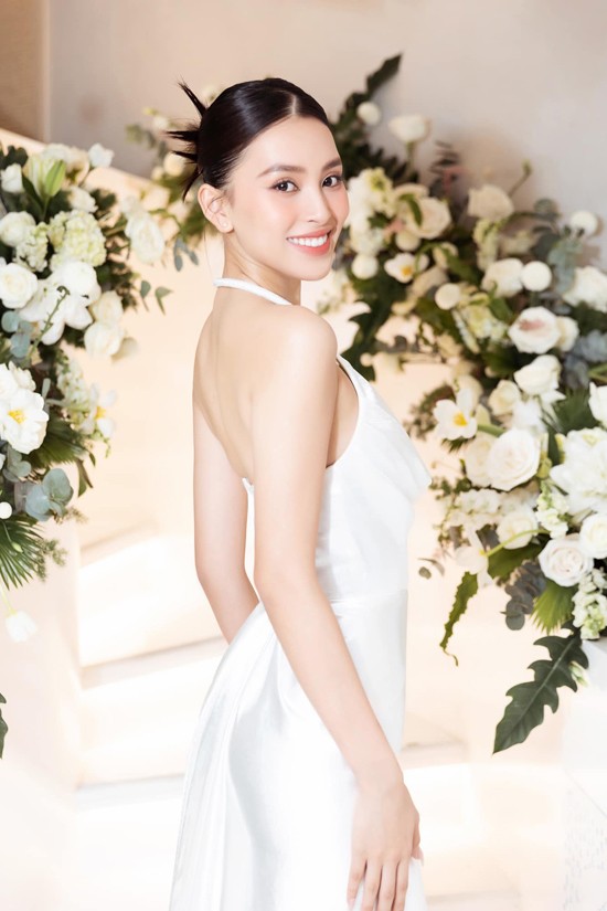 Hoa hậu Việt Nam 2018 làm tóc búi cao, chọn tông trang điểm hợp xu hướng mùa hè khi diện váy khoe vai trần đi sự kiện.