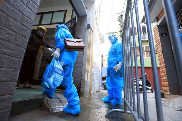 Medical workers hand over medicine to a COVID-19 patient treated at home (Photo: VNA)
