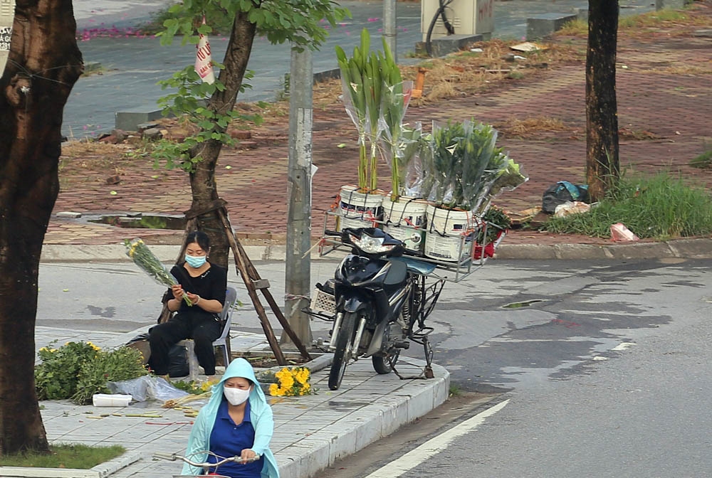 Một người phụ nữ kinh doanh hoa tươi ngay trên vỉa hè.