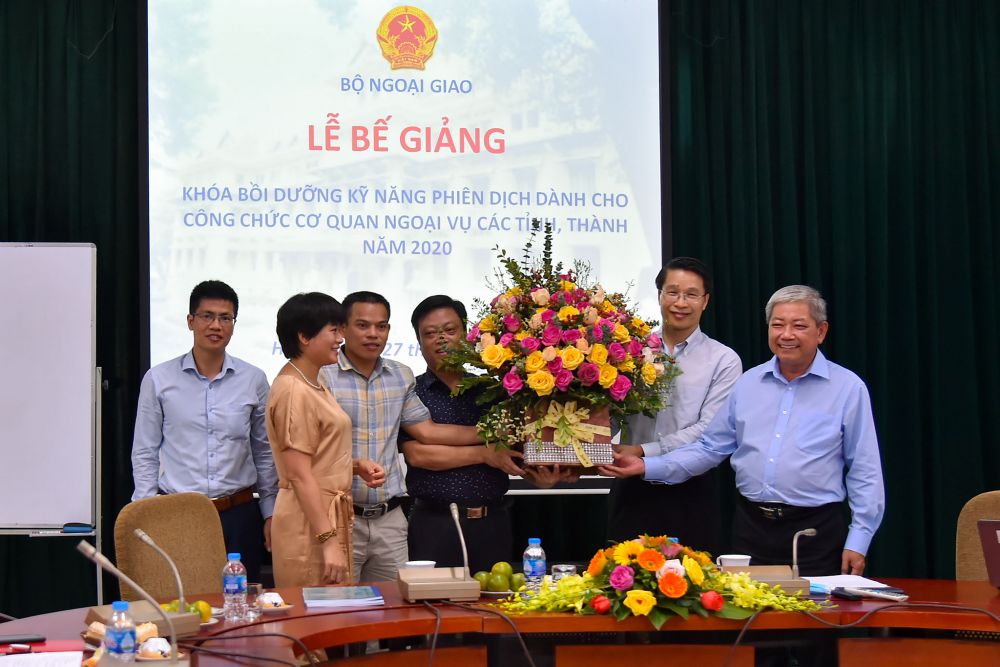 Đại diện các học viên tặng hoa cho ông Phạm Bình Đàm, Giám đốc Trung tâm Biên-Phiên dịch Quốc gia và ông Cao Trần Quốc Hải, Phó Cục trưởng Cục Ngoại vụ. be-giang-khoa-boi-duong-ky-nang-phien-dich-cho-can-bo-ngoai-vu-cac-dia-phuong